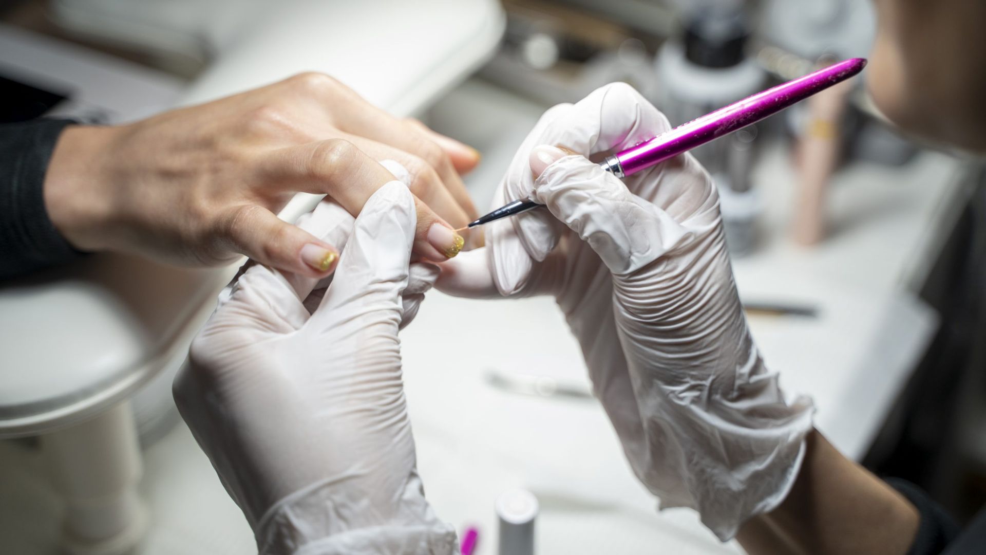 Nail technician applying final touches to a BIAB manicure during the finishing stage.