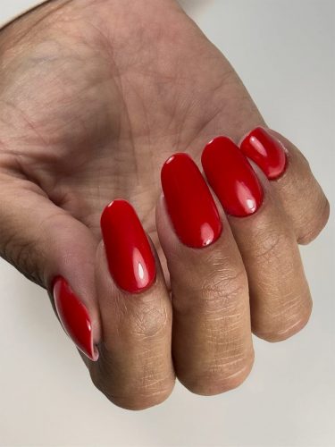 Nail extensions finished with red gel polish and a smooth glossy salon finish.